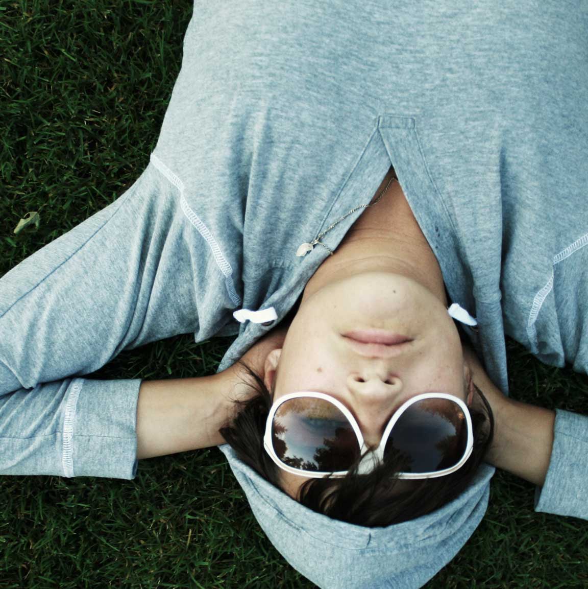 Boy with sunglasses and hoodie laying in the grass